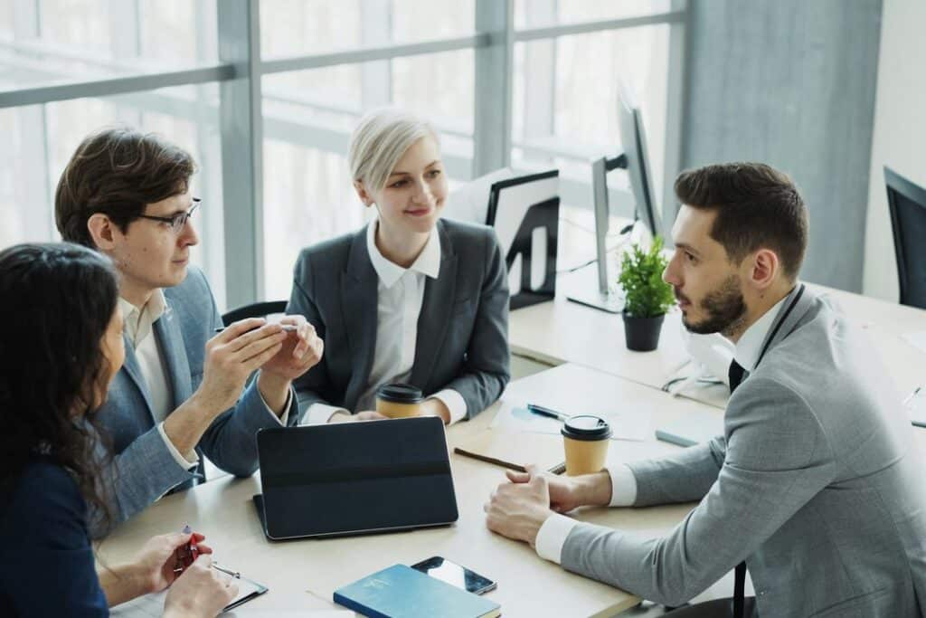Cuatro integrantes de un equipo directivo conversan alrededor de una mesa de trabajo en una oficina