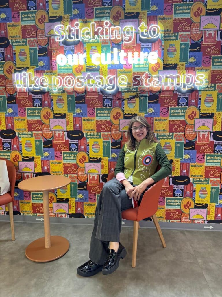 María Isabel Holguín en las oficinas de un cliente, frente a un mural sobre su cultura organizacional